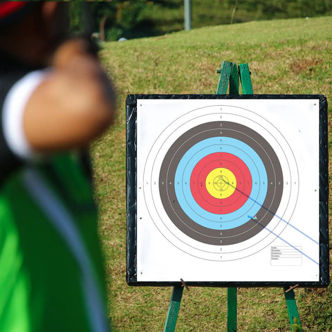 Archer aiming at 100 Pack Bullseye Paper Archery Targets With 4 Pins For Easy Setup, 16x16 Inch 10 Ring Targets on stand.