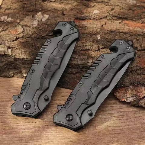 Two Black Serrated Folding Knife With Dual Edge Design For Outdoor Camping, Fishing And Hunting resting on a wooden surface.