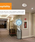 Rugged Wireless LoRaWAN Smoke And Heat Detector With No Fuss Setup And Marathon Battery Life Featuring Slick Cloud Monitoring For Heavy Duty Commercial Sites in a hotel hallway with smoke icon.