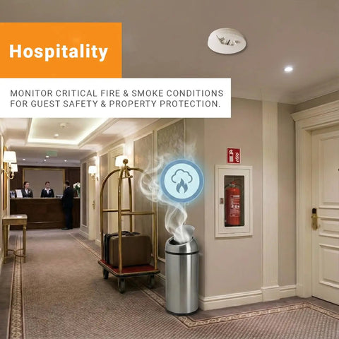 Rugged Wireless LoRaWAN Smoke And Heat Detector With No Fuss Setup And Marathon Battery Life Featuring Slick Cloud Monitoring For Heavy Duty Commercial Sites in a hotel hallway with smoke icon.