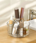 360 Degree Rotating Makeup Organizer Turntable on vanity with skincare bottles and brushes, five clear compartments.