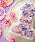 Number one cake decorated with pink, purple, and blue icing rosettes, surrounded by pink candies and a lollipop on a tray