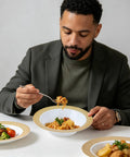 Man enjoying pasta in Sturdy Reusable Plastic Bowls With Gleaming Gold Grid Rim, 12 Ounce White Bowls Perfect For Gameday Grills And Big Group Feasts, Bpa Free Food Grade Durable Bulk 100 Pack.