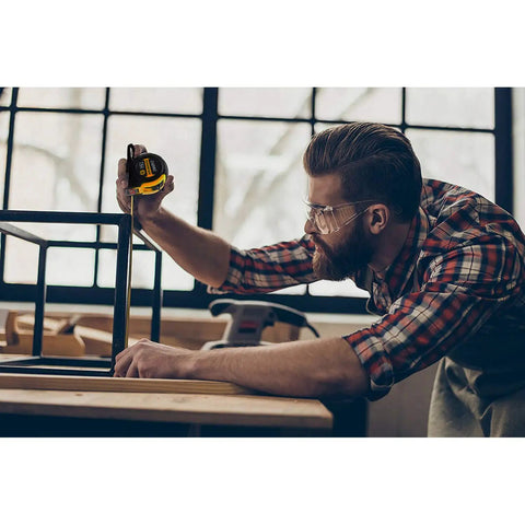 Man using 25 Ft Measuring Tape With Easy Read Decimal Scale, Dual Sided Ruler In Metric And Inches, magnetic tip on table