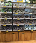 A display rack showing assorted packaged snacks in bins, featuring a wooden storage base for easy access.