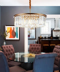 23 Inch 8 Light Modern Crystal Chandelier With Dual Gold Rings hanging in an elegant dining room with plush chairs and glass table.