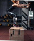 Athlete jumping onto a box in a gym with Six Piece Flexible Draw Latch Kit With Rubber Lock Latches attached to the box front.