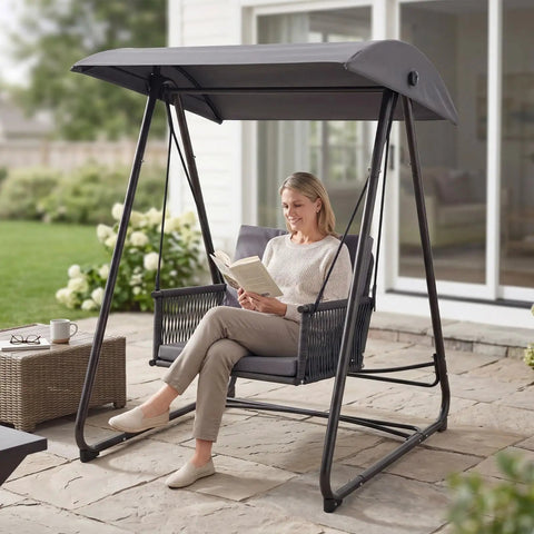 Woman reading on porch swing with stand and canopy, all-weather grey heavy duty swing chair with 400 lb capacity for outdoor relaxation.