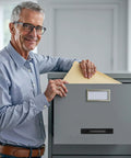 Man filing document in a gray filing cabinet drawer, office setting