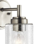 Close-up of Winslow 9.25 Inch Wall Sconce in Brushed Nickel with Clear Seeded Glass showing light bulb and mounting detail.