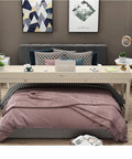Roomy Rollin Overbed Laptop Desk Featuring Sturdy Guard Rail And Smooth Lockable Wheels Solid Wood Bedside Tray on a bed with pillows.