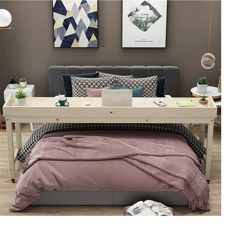 Roomy Rollin Overbed Laptop Desk Featuring Sturdy Guard Rail And Smooth Lockable Wheels Solid Wood Bedside Tray on a bed with pillows.