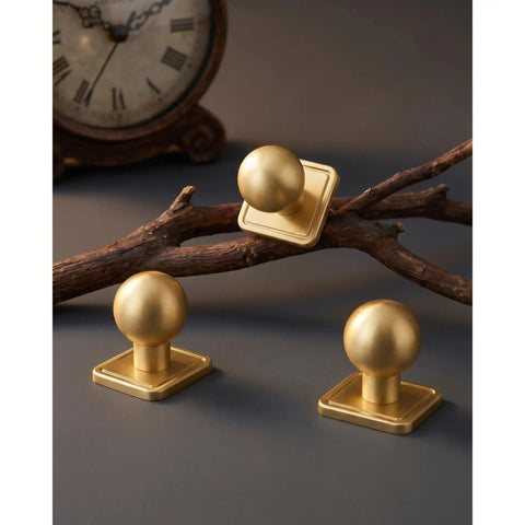 Slick Gold Zinc Alloy Cabinet Knobs With Premium Square Backplate And 1 Inch Round Ball Pulls For Kitchen Drawers Dressers Wardrobes Top Shelf Cupboard Furniture Hardware displayed on a wooden branch.