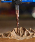 Carbide end mill bit with spiral flutes, bronze-colored; cutting wood (close-up view)