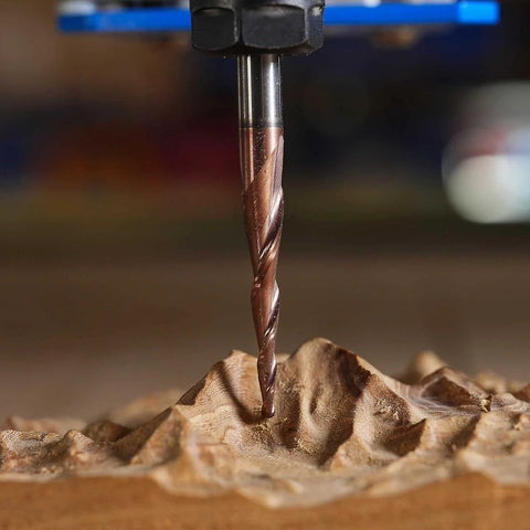 Carbide end mill bit with spiral flutes, bronze-colored; cutting wood (close-up view)