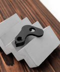 Outside Frame Bicycle Tail Hook For Folding And Fixed Gear Bikes, Durable Metal Rear Derailleur Hook In Black on wood surface