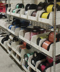Heavy Duty Plastic Stacking Storage Bins In Beige Featuring A Six Pack Bundle With Reinforced Structural Frames For Rock Solid Load Support And Top Shelf Garage Organization System on metal racks filled with colored spools.