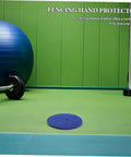 Blue Wool Felt Fencing Hand Guard Pads on green exercise mat, surrounded by fitness equipment.