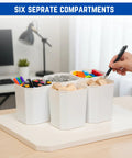 Desk organizer with six separate compartments holding markers, clips, and blocks in a home office setting.