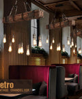 Rustic Industrial 8-Light Pendant Chandelier For Dining Room And Kitchen Island in cafe setting with wooden beams and vintage bulbs.