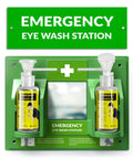 Front view of green wall-mounted emergency eye wash station with dual bottles, white cross symbol, and central mirror.