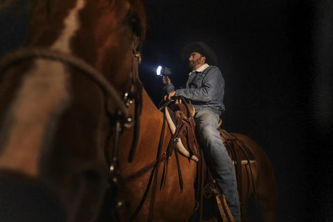Man on horse using 6000 Lumen Rechargeable Handheld Spotlight Flashlight With Car Charger Adapter REVO Portable Outdoor Beast at night