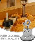 Hand electric drill bracket on wooden workbench with sawdust, close-up of clamping mechanism for precise drilling.
