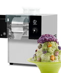 Heavy Duty Commercial Snow Cone Shaver Grinding Down Ice Blocks To Whip Up 198 Pounds Of Silky Shaved Flakes Daily With Tough Steel Cutters And Dependable Air Cooling For Street Vendors And Dessert Shops. Silver stainless steel machine with ice bowl.