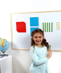 Child using Magnetic Base Ten Blocks For Math, Jumbo 131 Piece Set With Place Value Blocks on a whiteboard in classroom.