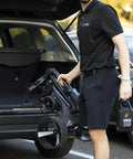 User loading Zip Navigator All Terrain Electric Golf Cart With No Sweat Zip Fold Frame into car trunk in gloss black.