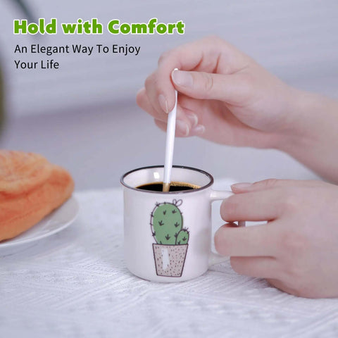 Hand stirring coffee in a ceramic mug with cactus design on a table with a napkin.