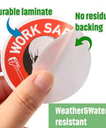 Close-up of a hand peeling a laminated, water-resistant hard hat sticker from a 300-piece Funny Toolbox Decals pack for helmets.