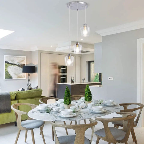Three Light Pendant Lighting With Clear Glass And Adjustable Silver Cord In Brushed Nickel, over a dining table in modern kitchen
