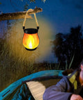 USB Charging Solar Lantern For Outdoors And Travel hanging from tree branch at campsite with soft glow