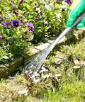 Person using Adjustable 17 To 63 Inch Thatch Rake With 24 Steel Tines for garden cleanup of leaves and debris near flowers.