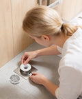 Woman installing Odor Stopper for Shower - Anti-Odor Mini Bottle Trap Design in a floor drain.