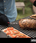 Person using iGrill Pro Stainless Steel Meat Probe With Four Color Coded Sleeves And Handy Storage Wrap For Simultaneous Monitoring Of Four Probes On iGrill Mini 2 And 3 Thermometers on grilled meat