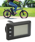 36V Electric Bike LCD Display Panel With 5 Pin Waterproof Interface for 22.2mm Handlebar, shown next to a folding bike in use.