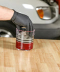 ARES 54036 bearing packer kit, red base with clear upper chamber, held by gloved hand.