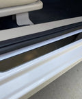 Badass Level Stainless Steel Door Sill Scuff Plate Guards For Rivian R1S R1T R2 shown on white vehicle entry step, protecting from scratches.