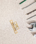 Brass Door Catch Hardware Set With Adjustable Spring Ball Latch for cabinets and closets, shown with various tools on a table.