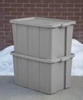 Tough As Nails 30 Gallon Storage Bins With Secure Lids stacked gray heavy duty plastic totes against brick wall.