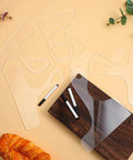 Slick Clear Acrylic Charcuterie Board Templates Kit With Three Woodworking Pens on a wooden cutting board with a loaf.