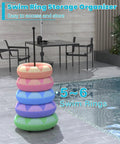 Sturdy Metal Pool Float Rack Organizer For Poolside Storage Holds 5 To 6 Swim Rings by the pool with pastel-colored rings.