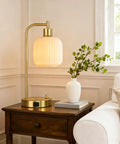 Industrial Touch Control Desk Lamp With Dual USB Ports And Outlet next to a vase on a wooden nightstand in a living room.