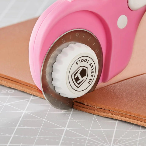 45mm Rotary Cutter With Five Extra SKS7 Stainless Steel Blades, Ergonomic Pink Handle, Safety Lock, shown cutting leather