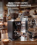 Pro Commercial Coffee Grinder With 64mm Flat Burr And Smart Touch Screen Weight Based Dosing For Espresso Brewing, displayed in a cafe setting.