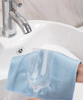 Blue Puomue microfiber glass cleaning cloth, 12 x 16 inches, lint-free, used to wipe a wine glass.