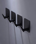 Matte black adhesive hooks 4 pack on wall, ideal for towels, coats, kitchen use. Adhesive Hooks 4 Pack Towel And Coat Hooks For Wall Mounting.