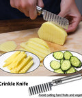 Stainless steel crinkle knife with ridged blade slicing a potato on a cutting board; pineapple and cucumber slices nearby.